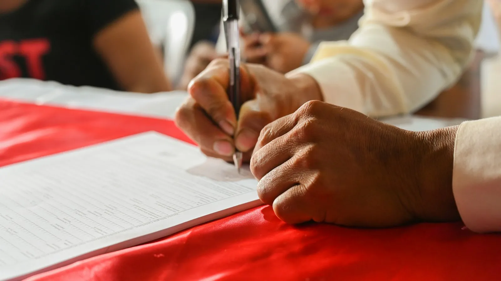 Mãos assinando um documento sobre a mesa